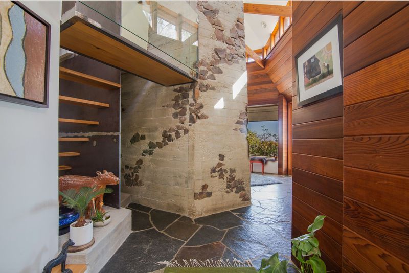 A massive stone fireplace surrounded by walls of redwood and stone floors.