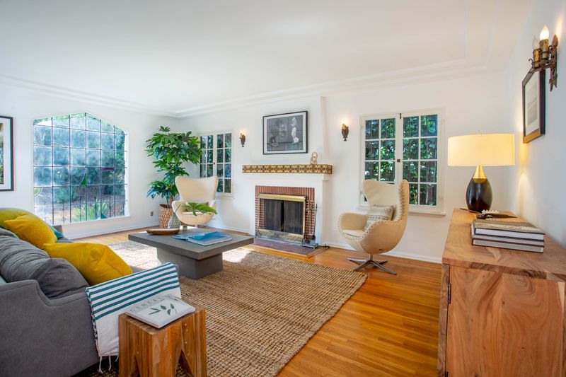 Bright living room with casement windows, fireplace, and a gray coffee table and sofa.